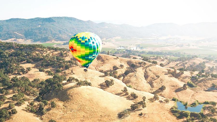 An aerial view overlooking a valley featuring a hot air balloon.