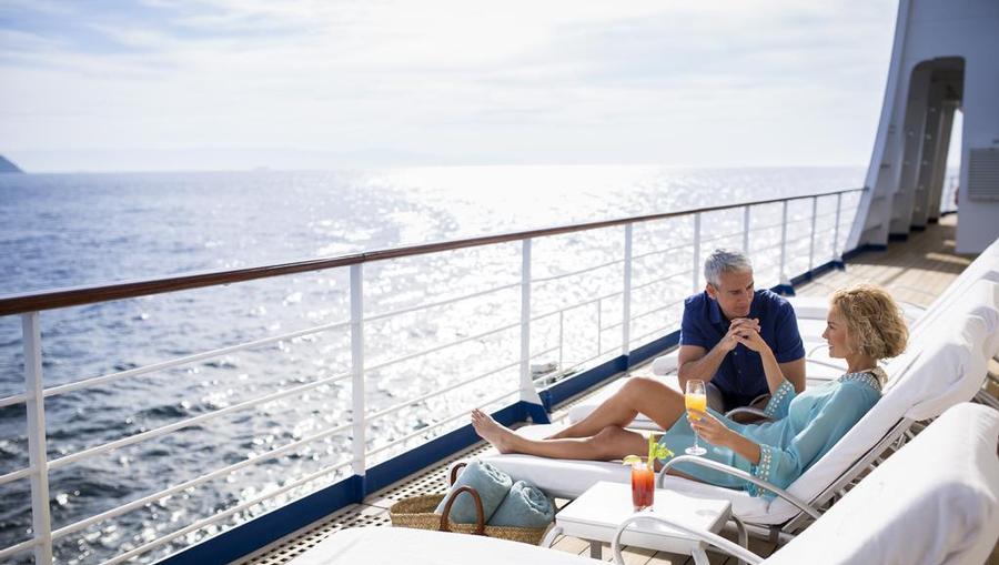 Couple enjoying drinks out on the ship deck.