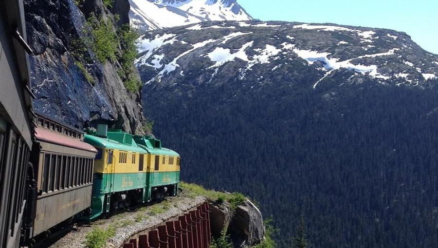 A view of the Alaskan Railroad train curving around a mountain in Alaska.