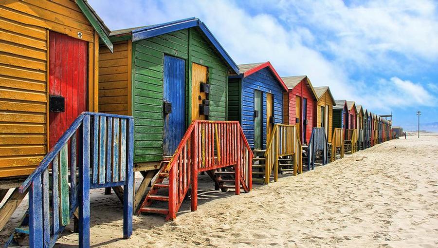 A view of colorful cabanas on a white sand beach.