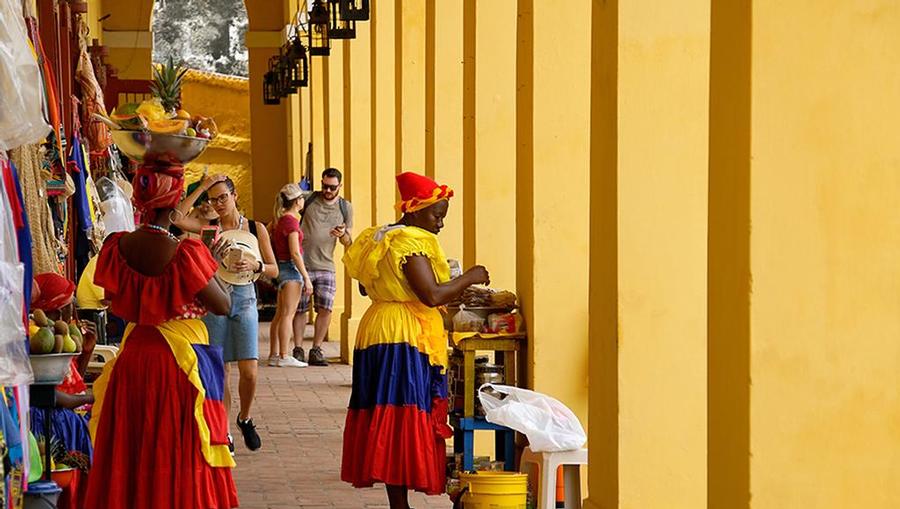 Women dressed in traditional clothing and people shopping at a shopping market in Cartagena,Colombia.
