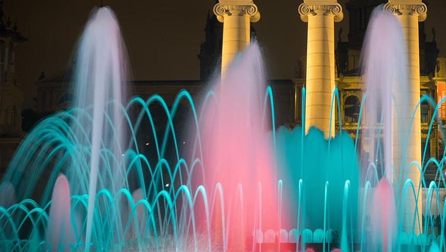 Hues of blue and red shine from the streaming water spraying in unison at the Magic Fountain in Barcelona, Spain.