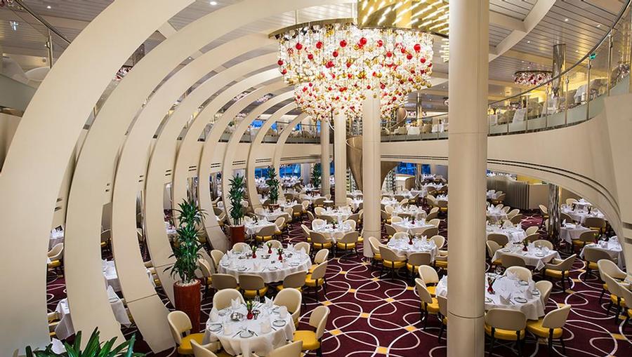 A view of the Dining Room onboard the Holland America Koningsdam and its stunning table settings and chandelier.