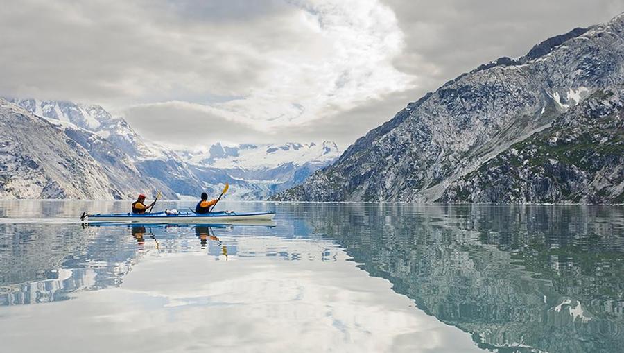 Kayakers on the calm waters at Glacier Bay National Park with stunning Alaskan landscapes in the background.