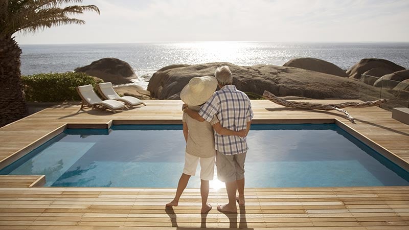 Couple embracing at resort pool with ocean in the background